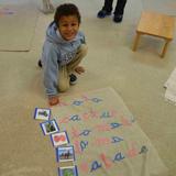 International Montessori School Photo - A 5 year old IMS student using the moveable alphabet to spell the words illustrated on cards.